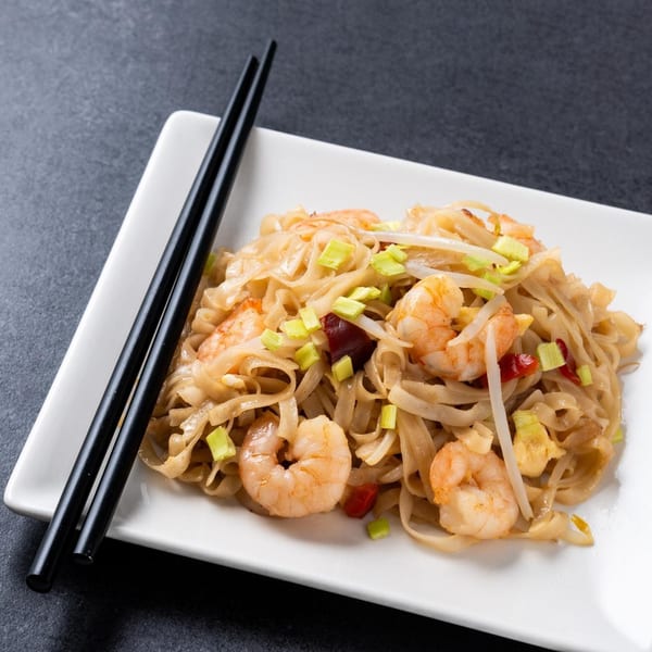 Thai Time's Pad See Ew with shrimp, wide rice noodles, and green onions on a white plate.