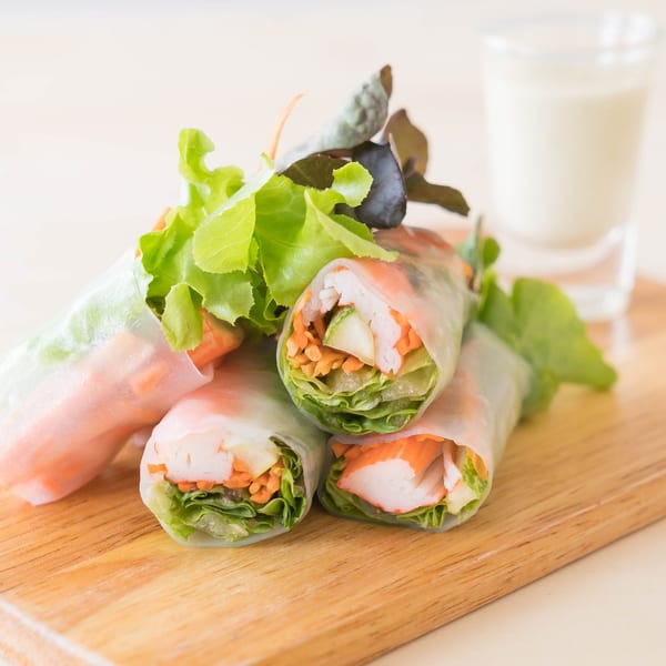 Fresh Thai spring rolls with crab, carrots, and lettuce, served with a creamy dipping sauce.